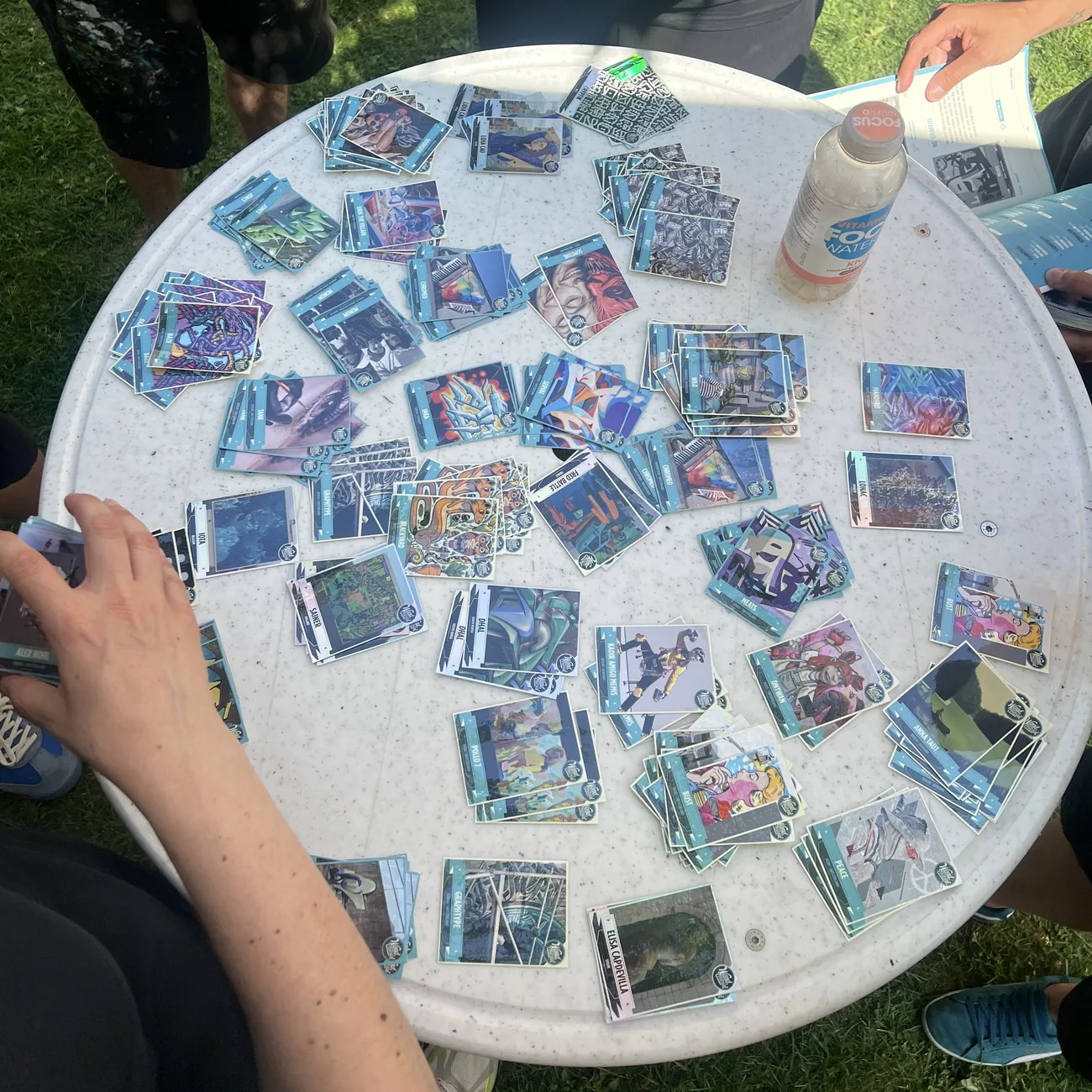 Festivalbezoekers vullen blauwe stickeralbums met verzamelstickers vol streetart die over een ronde tafel verspreid liggen