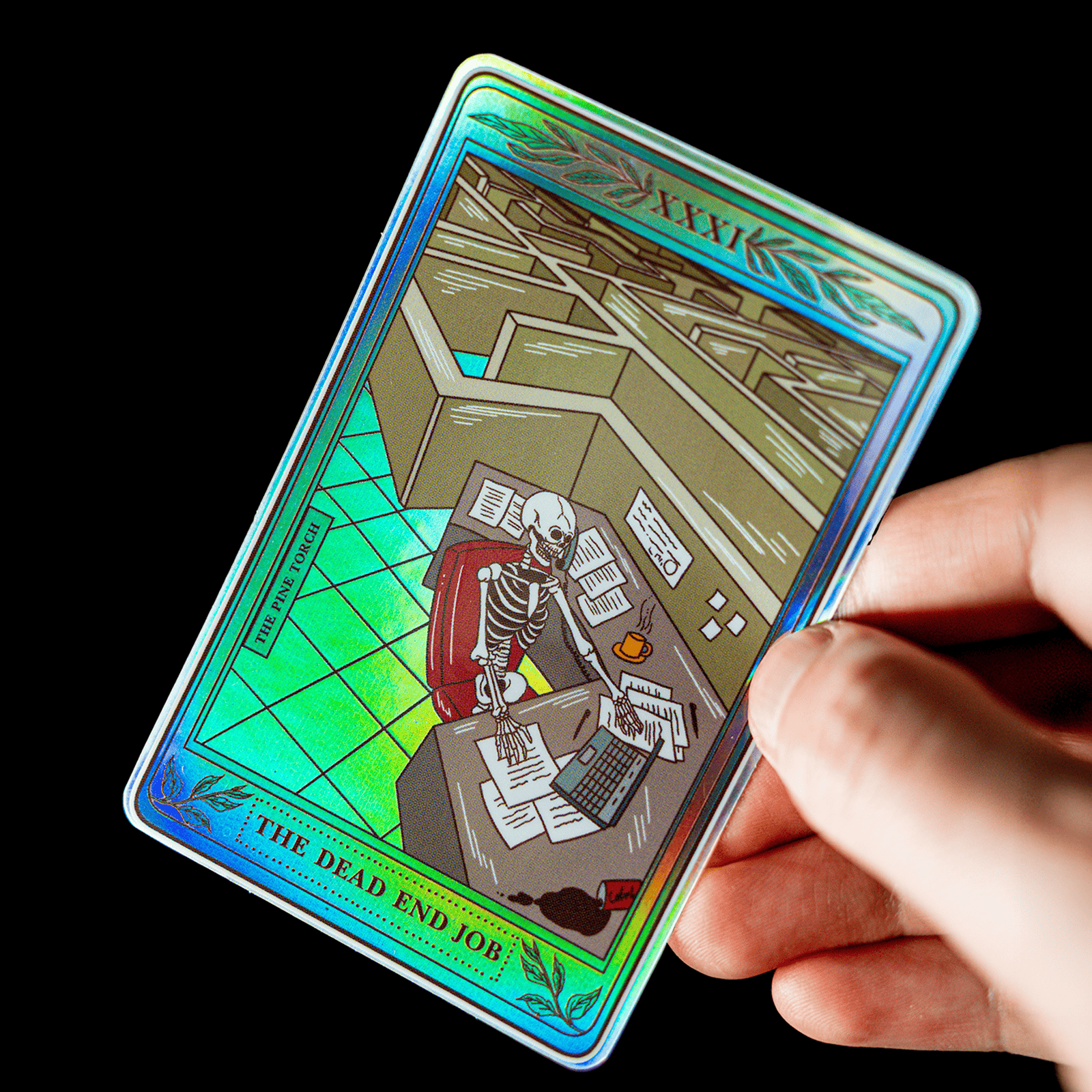 Hand met een holografische tarotkaartsticker met de titel "The Dead End Job" en een skelet achter een bureau